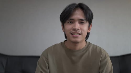 Smiling Young Man Talking To Camera Indoors