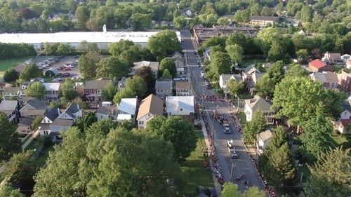 Aerial dolly shot of parade floats wrapping around town street corner during Independence Day celebr