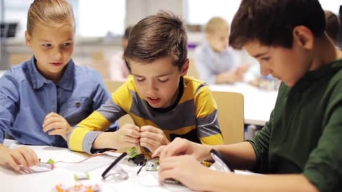 Happy children building robots at a robotics lesson achieve success with high five