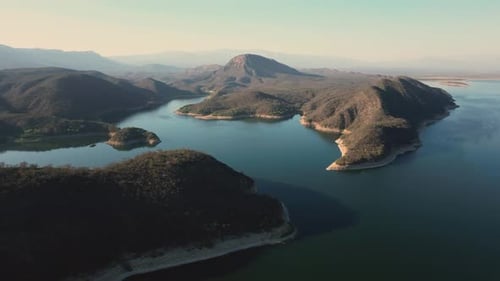 Aerial drone flying over a lake, water dam, with mountains at sunrise. Beautifull dreamy landscape