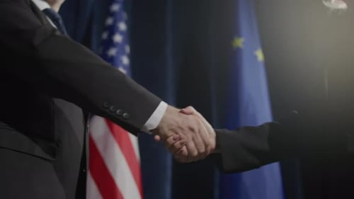 Handshake Between Representatives in Front of Flags