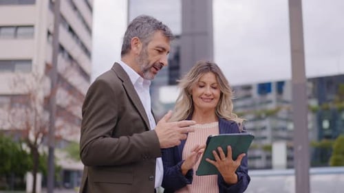 Business Colleagues Discussing Information on a Tablet Outdoors