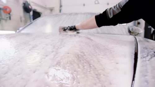 Scrubbing soap across red car hood