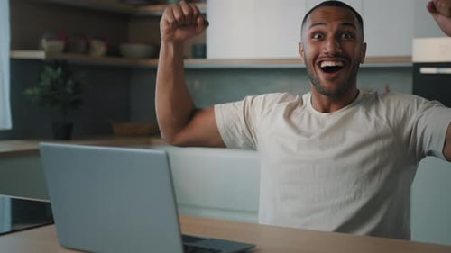 Excited Man with Laptop Celebrates at Home