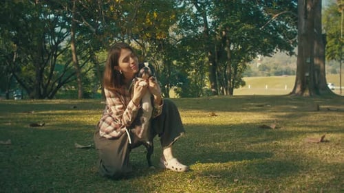 Woman Embraces Dog in Sunlight-Dappled Park