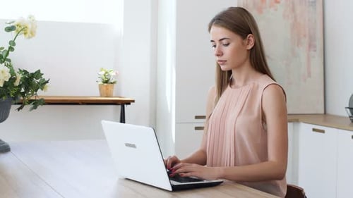 Woman Typing on Laptop at Kitchen Table
