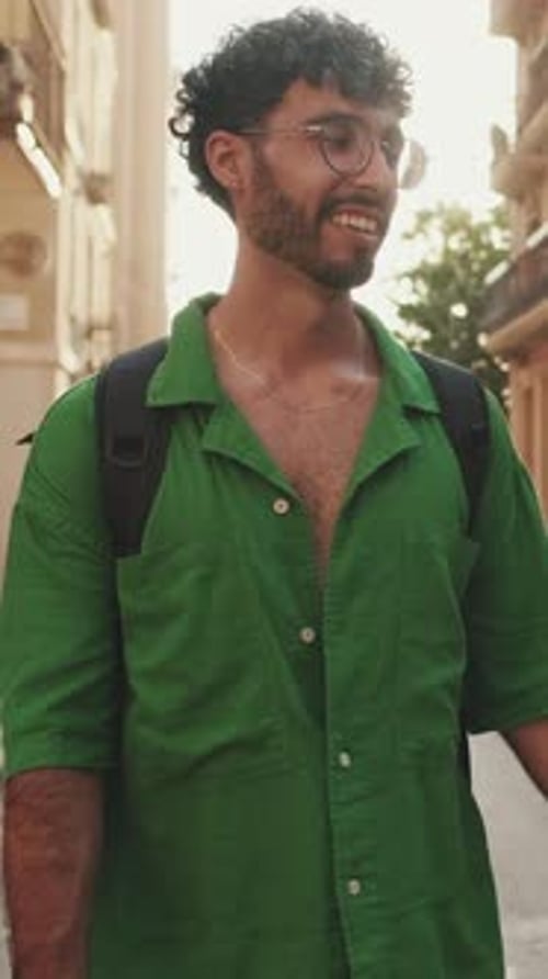 Brunette guy tourist with beard, dressed in green shirt, walks around city