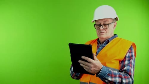 Senior Builder Looking Around Counts Quantity of Materials and Writes on Tablet
