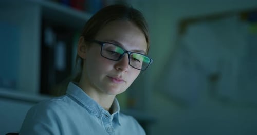 An Young Blond Successful Businesswoman with Glasses is Working with a Computer in an Office at Ni