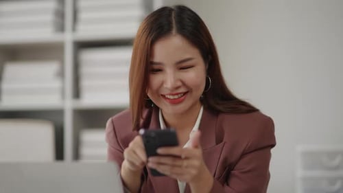 Smiling Woman Using Smartphone at Office Desk