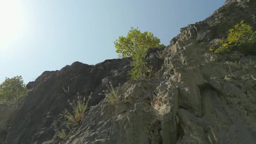 Aerial elevating and panning shot of rock cliff on summer day in Europe