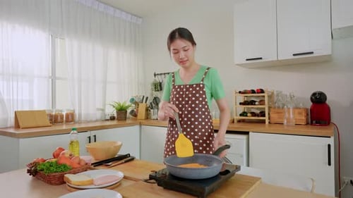 Woman Cooking in Kitchen with Vegetables and Frying Pan