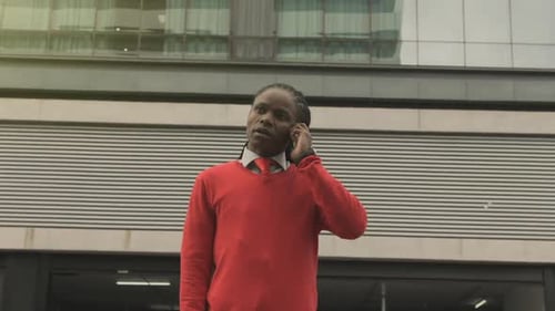 African american businessman confidently walking and talking on phone in modern city