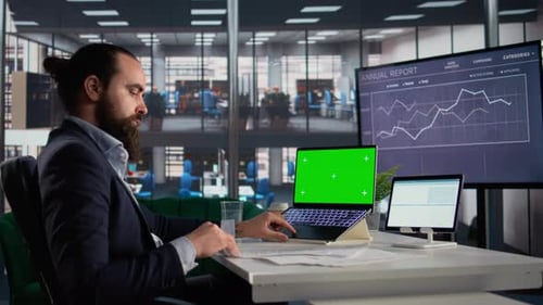 Man in Office Working on Laptop With Green Screen