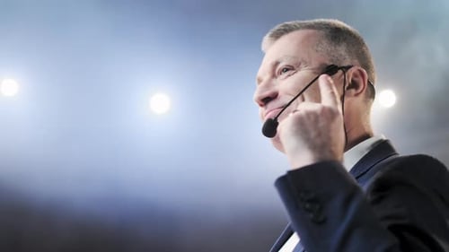Man Speaking at a Corporate Event with Microphone