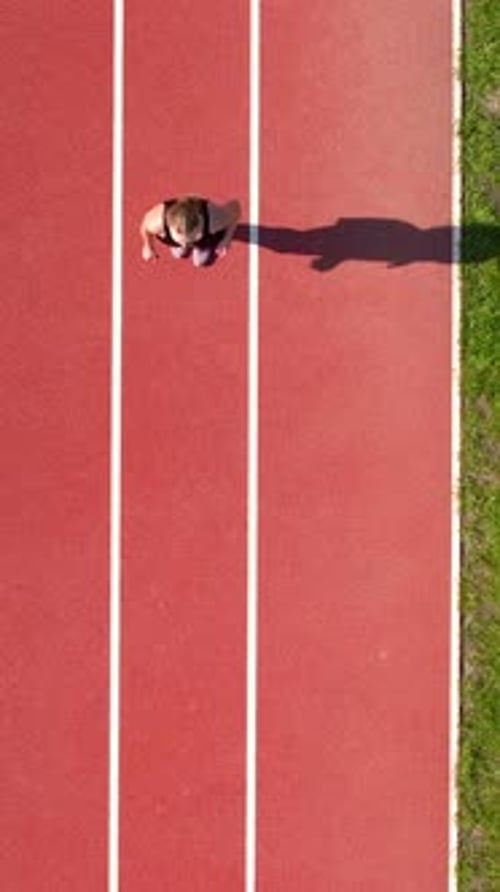 Top View Of Young Woman Running On Red Athletic Track