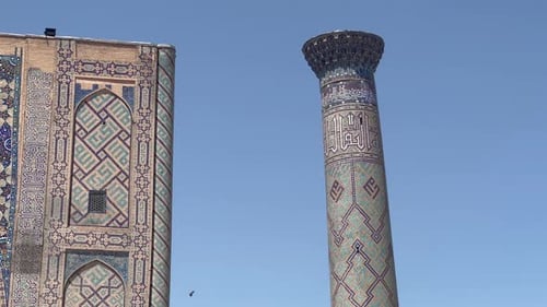 Des oiseaux entourent le minaret de la médersa d'Ulugh Bek sur la place du Registan, à Samarcande, en Ouzbékistan. Émerveillez-vous devant Intr