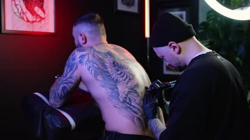 Professioneller Tattoo-Künstler macht ein Tattoo auf dem männlichen Rücken