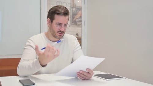 Middle Aged Man Feeling Upset while Reading Contract in Office