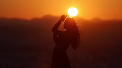 Woman Dances Silhouetted Against Brilliant Sunset