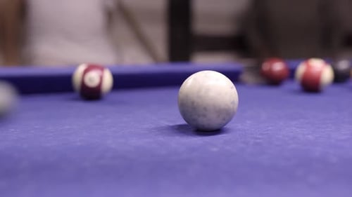 Pool stick hitting the white ball and scoring during a billiards table