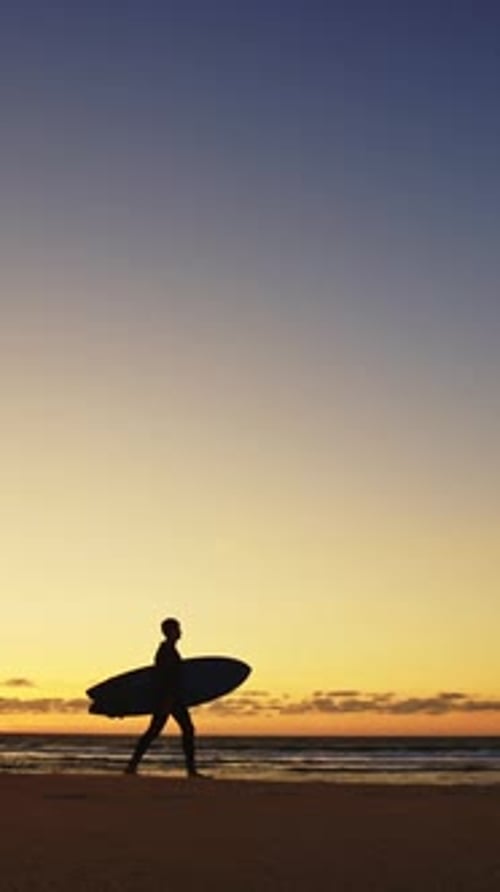 Silhouette of an Adult Man Walking at the Seashore Holding