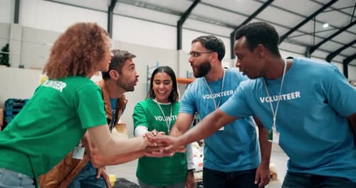 Happy people, volunteer and team with hands together for motivation or support at NGO warehouse