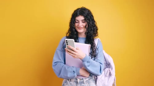 Young Woman with Backpack Using Smartphone in Studio