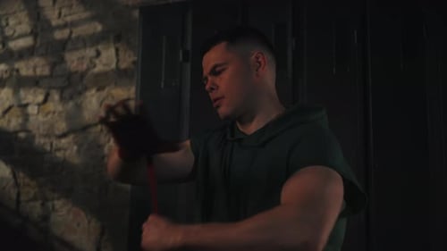 Man wrapping hands with bandage in dark setting