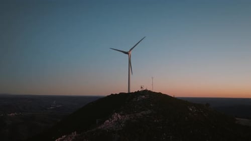 Scenic aerial view of windmill on top of the mountain in the sunset light. Big wind blades.