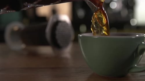 Tea is poured to the top of a mint green teacup on a wood table