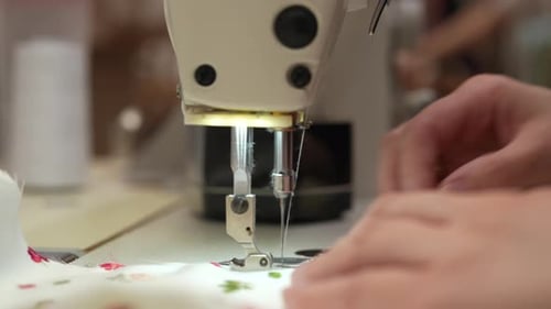 Closeup of Sewing Machine Stitching Floral Fabric Operated By Seamstress in Workshop Concept of