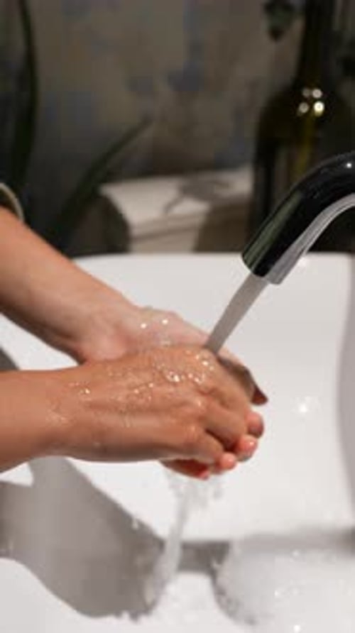 Woman Washing Hands Under Faucet with Soap