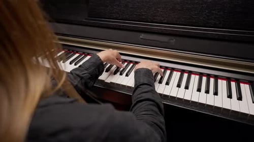 Close-up of a woman's hands in silver rings playing beautiful lyrical melody on the piano keys