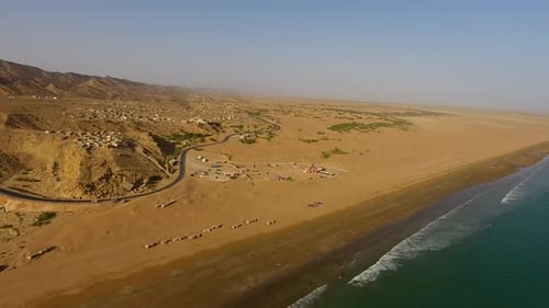 Aerial view of coastline, road, village, and desert along Arabian Sea, Pakistan.