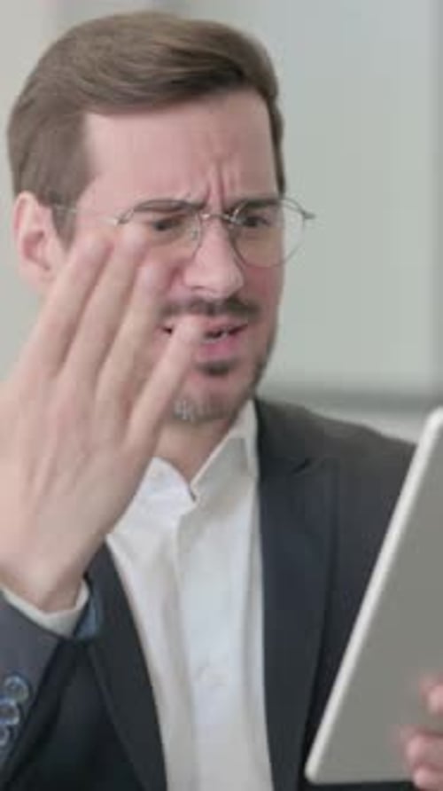 Man Looks at Tablet with Displeased Expression
