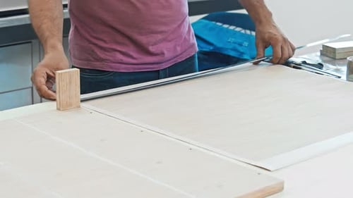 A Man is Taking Measurements of a Sizable Piece of Wooden Furniture at a Factory Using a Ruler
