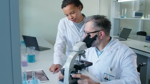 Scientists Using Microscope in Modern Laboratory