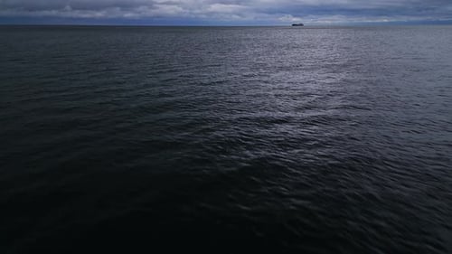 Aerial Drone View of a Calm Sea with Distant Clouds and a Lone Ship on the Horizon The Tranquil