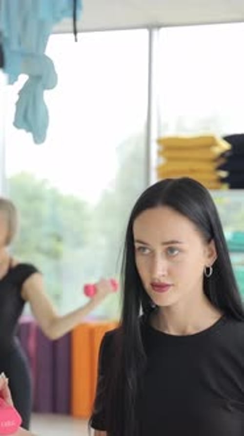 Young Women Doing Pilates in the Gym with Arms Raised Toning Muscles with Dumbbells Vertical Video