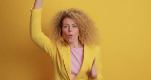 Excited woman with curly hair dances in studio