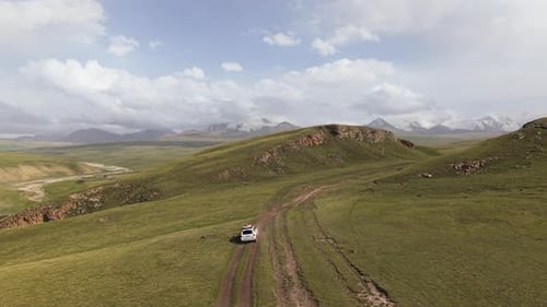 Aerial View of an Off-road Vehicle Driving Through The Mountain Hills In Kyrgyzstan.