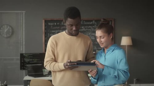 Two Programmers Discussing Data on Digital Tablet in Office