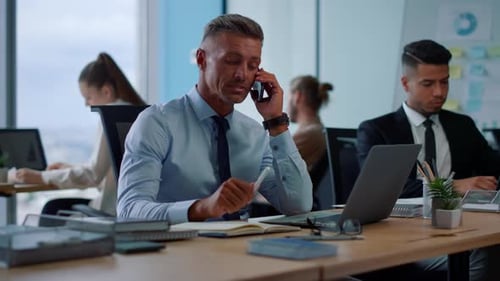 Smiling Businessman Talking on Smartphone in Office. Male Manager Having Conversation On