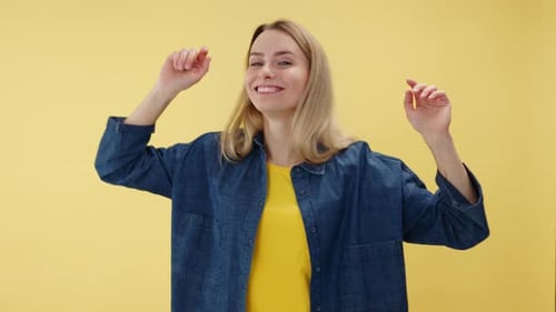Blonde Woman Dancing and Smiling on Yellow Background