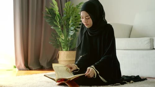 Portrait of Asian Muslim woman reciting Surah al-Fatiha passage of the Qur'an, in a daily prayer at