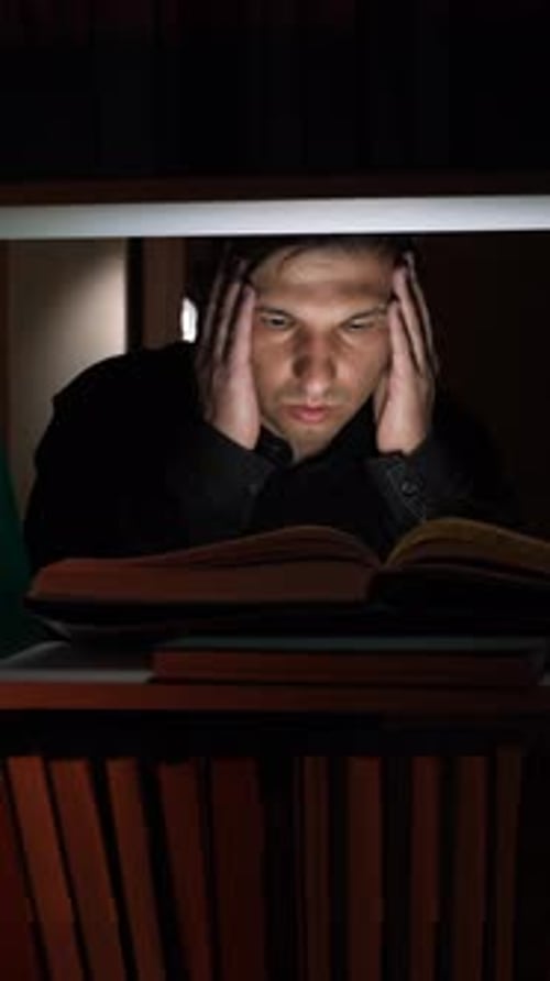 Vertical Video Focused Student Studying Late at Night in Dark Library Holding Head