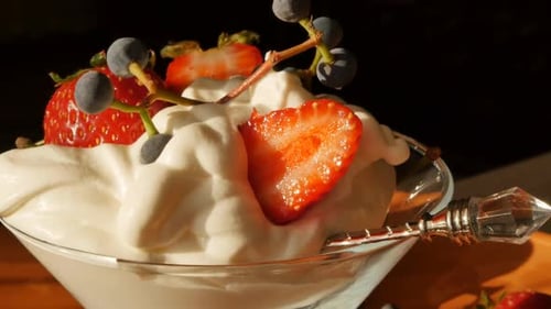 Extremely Closeup of a Glass Cup Filled with Whipped Cream with Red Fresh Strawberries and a Sprig