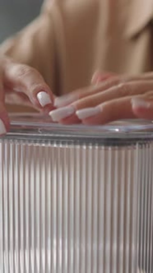 Woman Puts Lid on Plastic Container and Examines Utensil