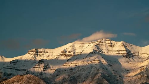 Timelapse of clouds moving over snow capped mountain at sunset